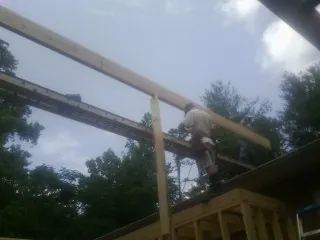Carpenter setting a ridge beam over a new addition frame — Ice Dam Removal by Roofing Brothers in Shoreham