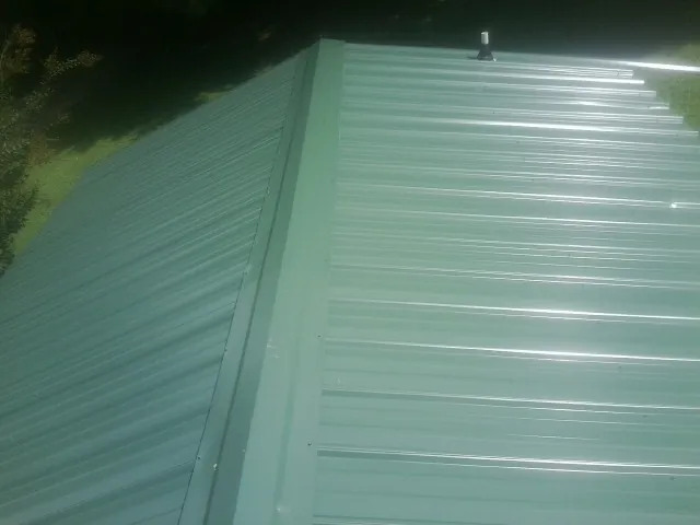 New green metal panels meeting at the ridge of a roof — Flat Roof Repair work by our crew in Shoreham
