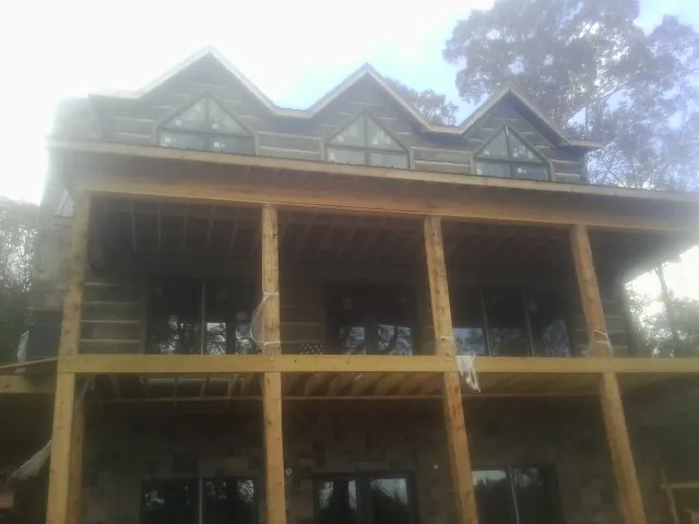 Dormers and porch framing on a large log home under construction — Roof Coating work by our crew in Shoreham
