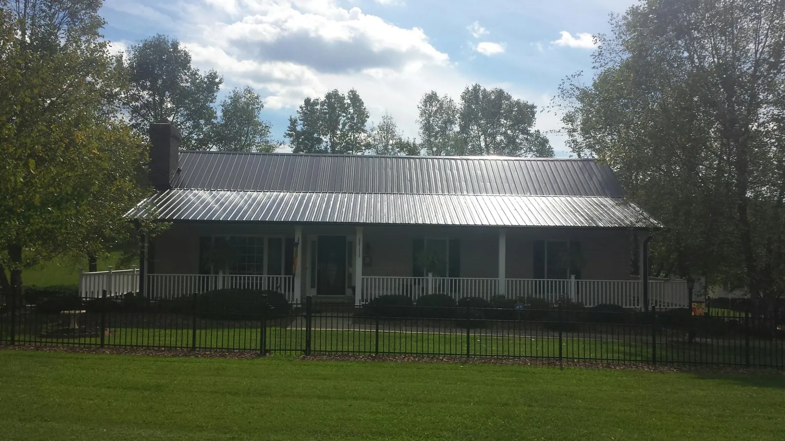 Gray metal roof on a brick ranch with a full width front porch — Gutter Guard Installation work by our crew in Shoreham