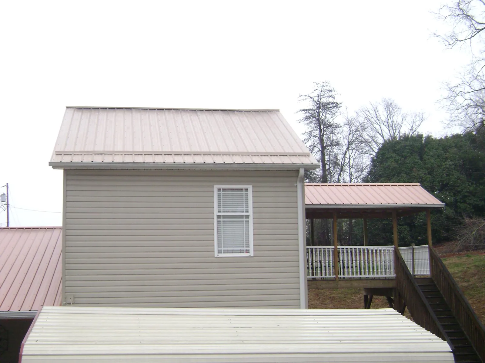 Tan metal roofs on a two story addition and attached porch, from a Roof Replacement job in Shoreham