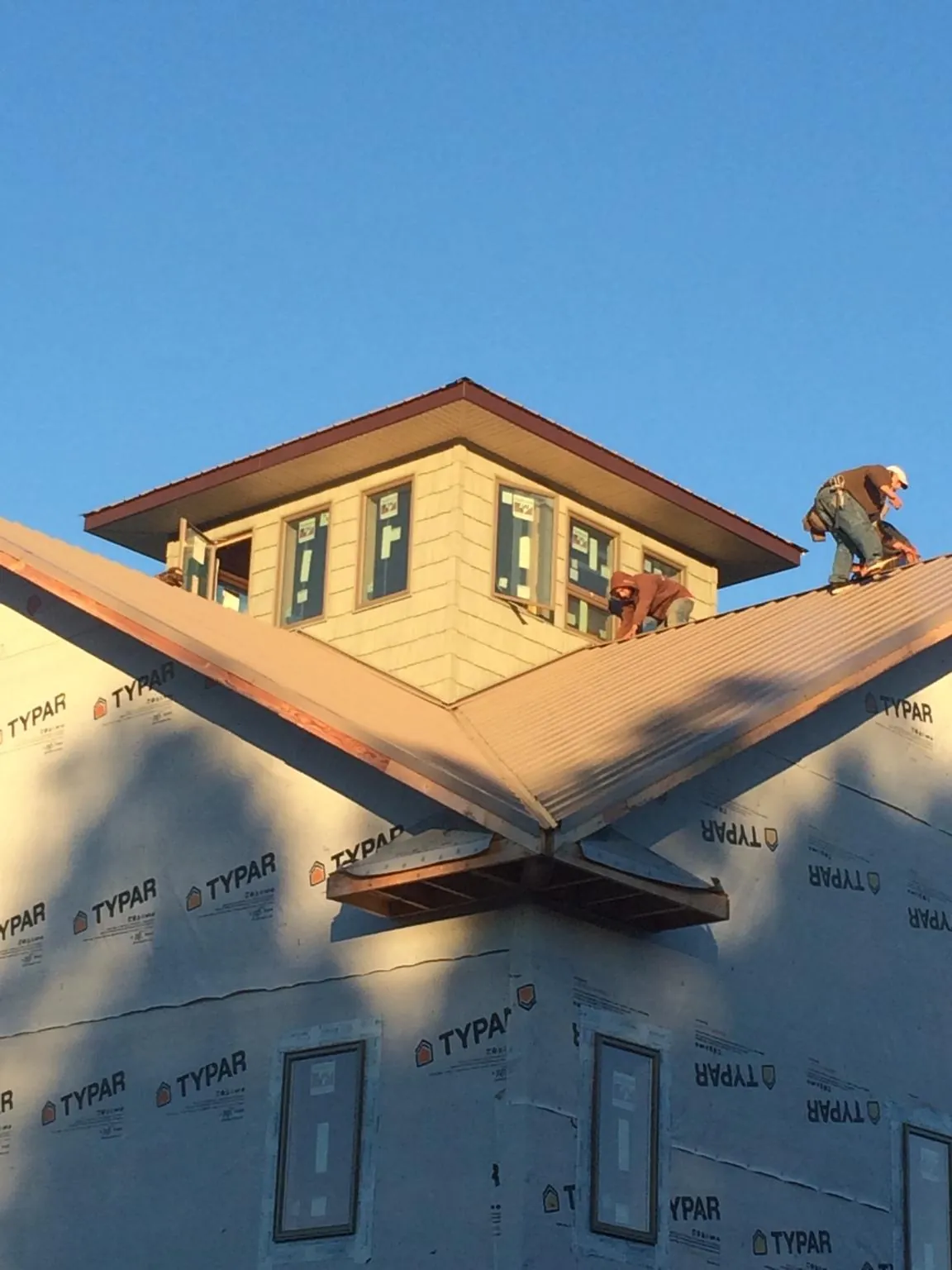 Roofers working around a rooftop cupola on a new metal roof at sunset — Roof Waterproofing in Shoreham by Roofing Brothers